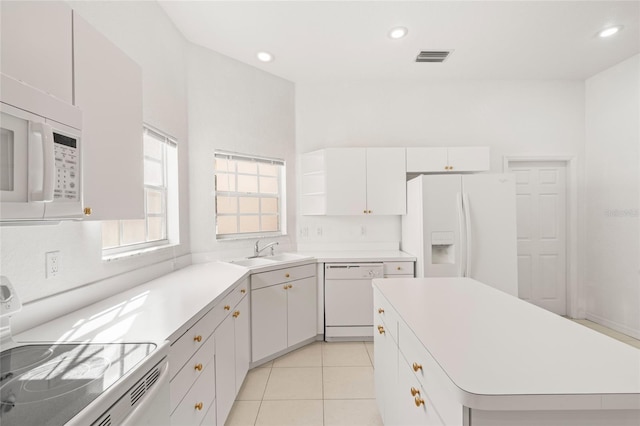 kitchen with sink, a kitchen island, white cabinets, white appliances, and light tile patterned floors