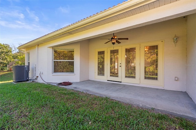 property entrance with a patio, ceiling fan, cooling unit, and a lawn