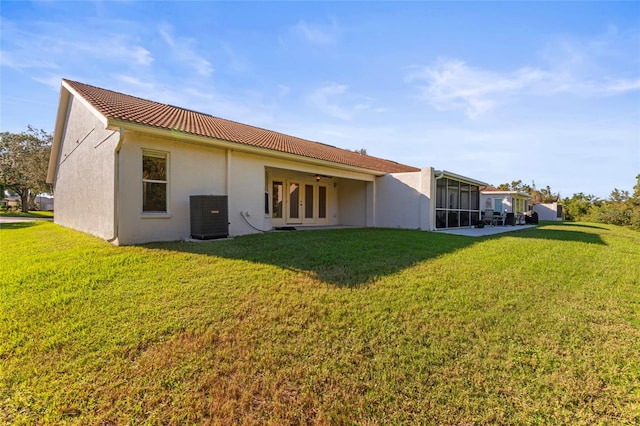 back of property with a lawn, french doors, and cooling unit