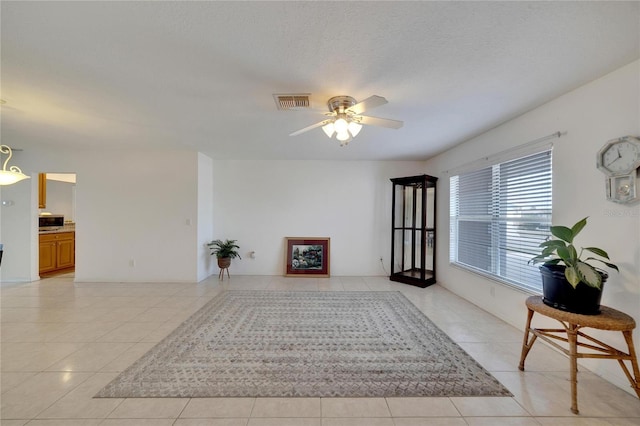 sitting room featuring light tile patterned floors, a textured ceiling, and ceiling fan