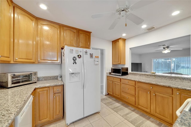 kitchen featuring light stone counters, light tile patterned flooring, white appliances, and ceiling fan