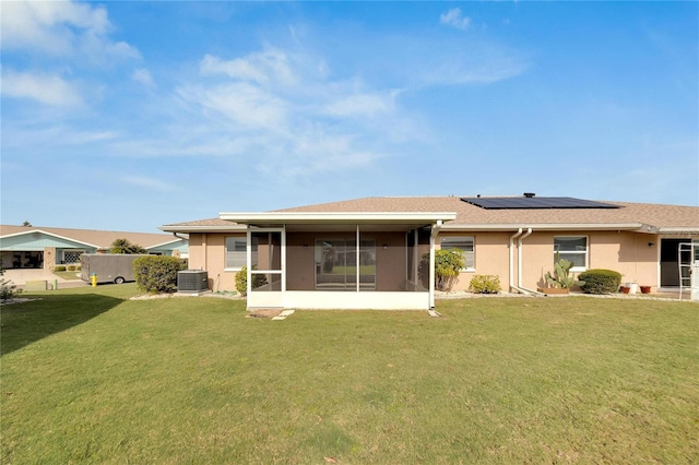 back of house with a sunroom, a yard, central AC unit, and solar panels