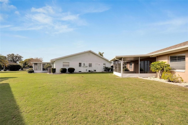 rear view of house with a lawn and a sunroom