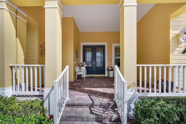 view of exterior entry with covered porch and french doors