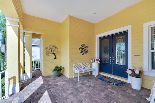 view of exterior entry with covered porch and french doors