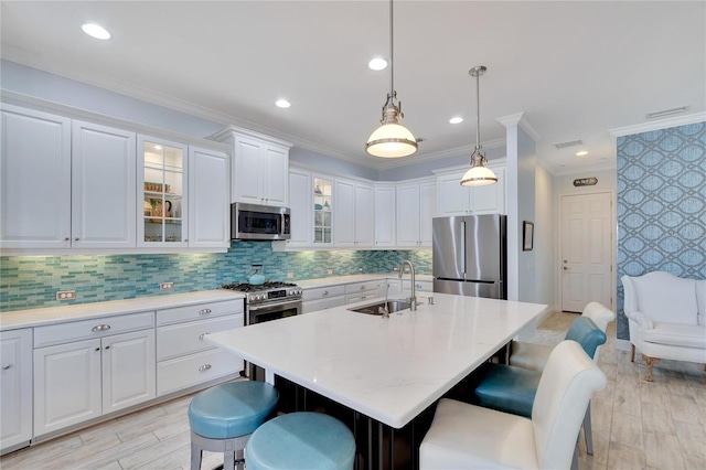 kitchen with sink, white cabinetry, stainless steel appliances, and a kitchen island with sink