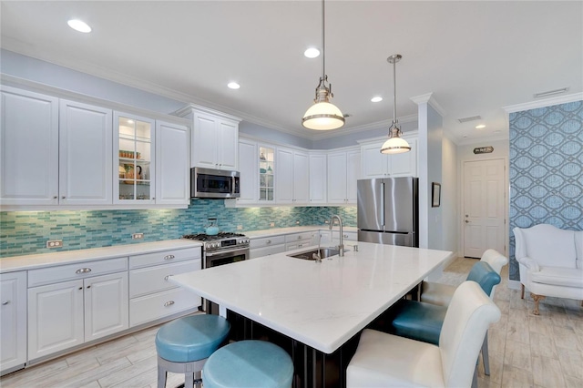 721 Manns Harbor Dr, Apollo Beach, FL 33572 - kitchen featuring appliances with stainless steel finishes, a sink, a kitchen bar, light countertops, and ornamental molding