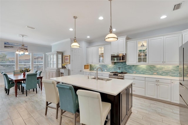 kitchen with white cabinets, stainless steel appliances, hanging light fixtures, and sink