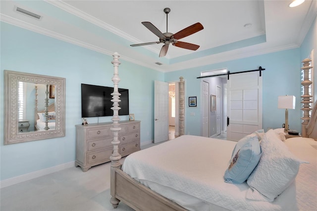 bedroom featuring ceiling fan, a barn door, ornamental molding, a tray ceiling, and light colored carpet