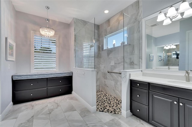 bathroom with vanity, a healthy amount of sunlight, a tile shower, and a chandelier