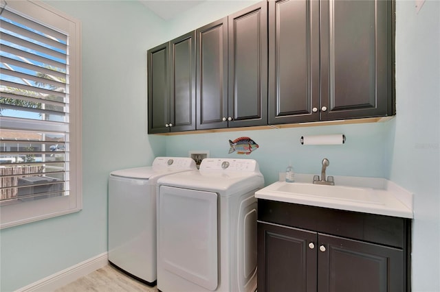 laundry area featuring cabinets, light wood-type flooring, washer and dryer, and sink