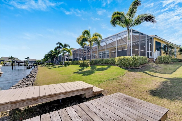 dock area with glass enclosure, a yard, and a water view