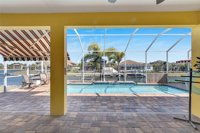 view of swimming pool with glass enclosure, a patio area, and a water view