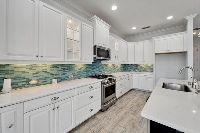 721 Manns Harbor Dr, Apollo Beach, FL 33572 - kitchen with appliances with stainless steel finishes, crown molding, white cabinetry, glass insert cabinets, and decorative backsplash