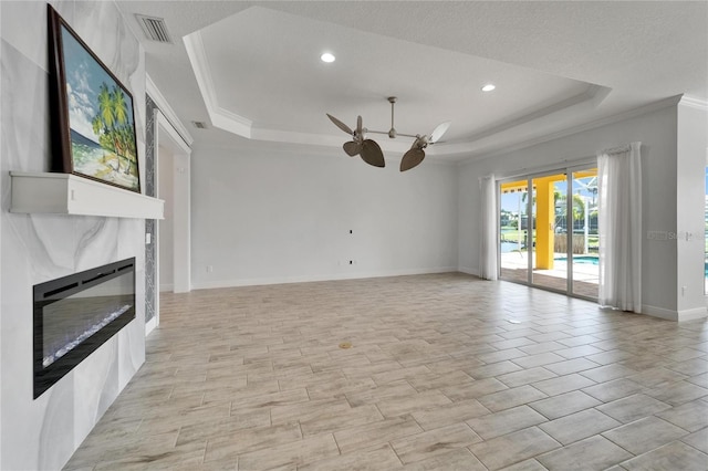 721 Manns Harbor Dr, Apollo Beach, FL 33572 - unfurnished living room featuring a raised ceiling, ceiling fan, crown molding, a glass covered fireplace, and recessed lighting