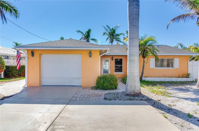 ranch-style home with stucco siding, a shingled roof, an attached garage, fence, and driveway