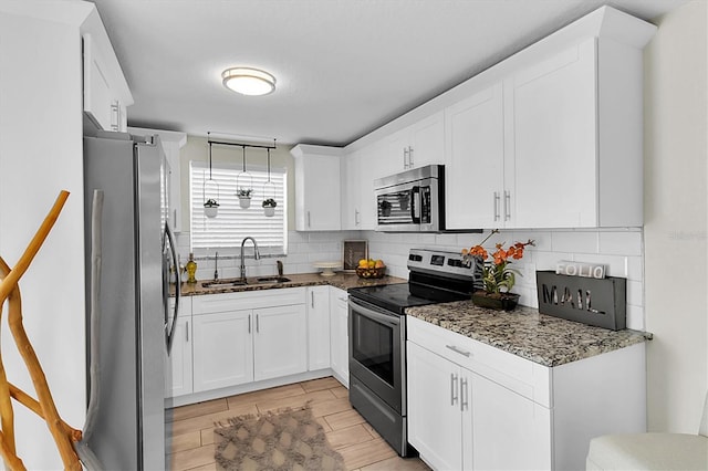 kitchen featuring dark stone counters, sink, decorative backsplash, white cabinetry, and stainless steel appliances