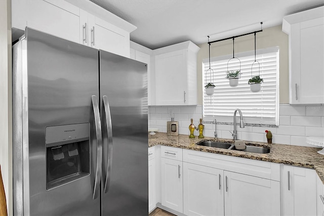 kitchen featuring white cabinets, stainless steel fridge, sink, and stone counters