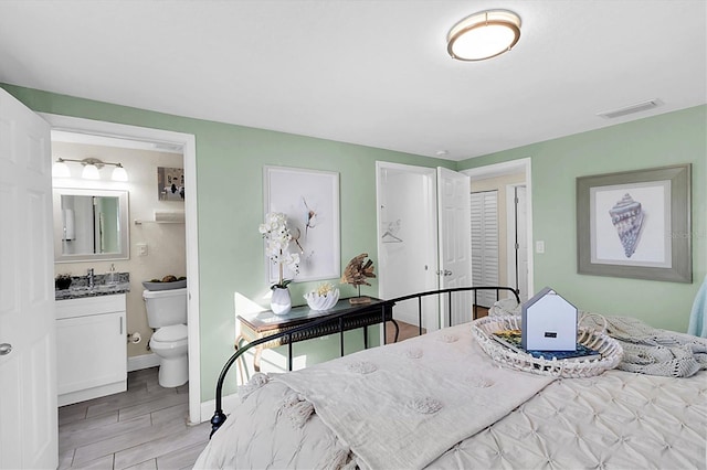 bedroom featuring ensuite bath and light hardwood / wood-style floors