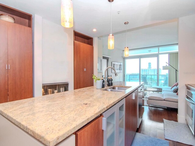 kitchen featuring light stone countertops, dark hardwood / wood-style flooring, sink, wine cooler, and hanging light fixtures