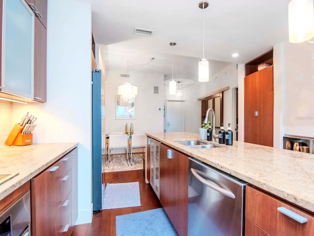 kitchen featuring dishwasher, sink, hanging light fixtures, light stone countertops, and dark hardwood / wood-style flooring