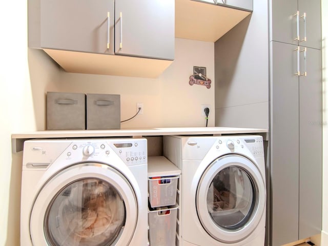 clothes washing area with washer and dryer and cabinets