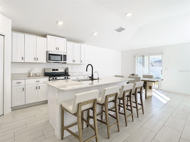 kitchen with a kitchen island with sink, sink, white cabinets, and appliances with stainless steel finishes