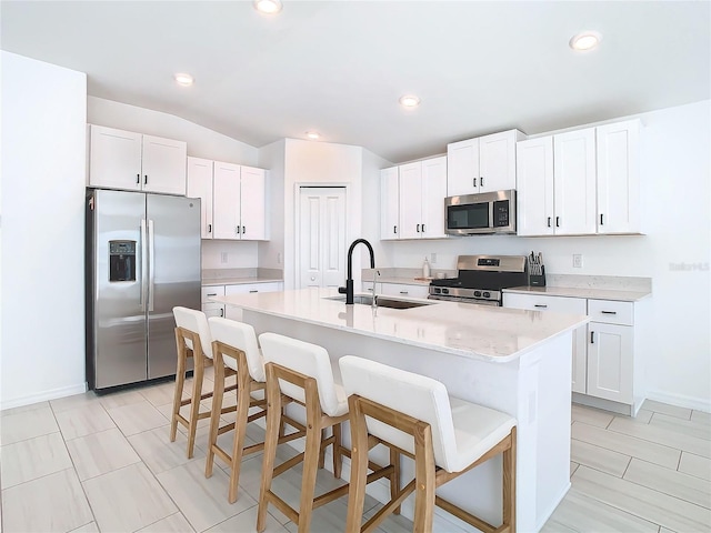 kitchen featuring white cabinetry, a kitchen island with sink, sink, and appliances with stainless steel finishes