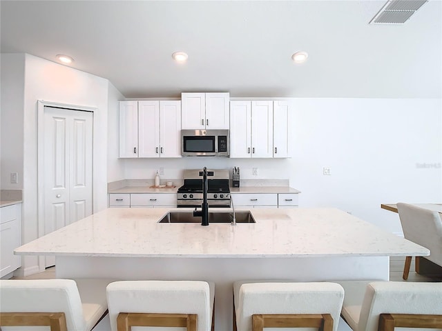 kitchen with a kitchen island with sink, white cabinetry, sink, and stainless steel appliances