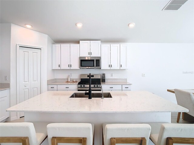 8849 Little Bluestem Dr, Land O Lakes, FL 34637 - kitchen featuring appliances with stainless steel finishes, a breakfast bar area, a sink, light stone countertops, and recessed lighting