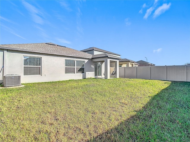 rear view of house with a lawn and central AC