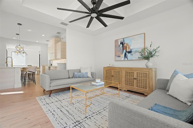 living room with ceiling fan, sink, and light hardwood / wood-style floors