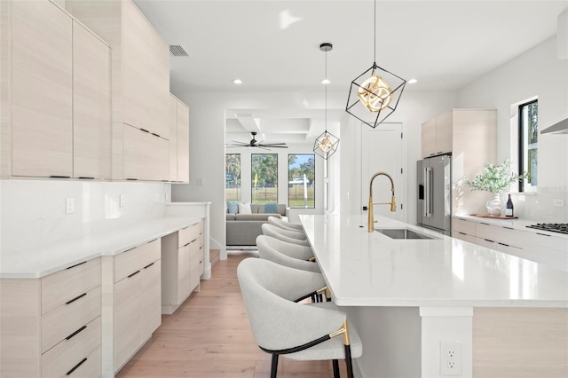 kitchen with sink, light hardwood / wood-style flooring, decorative backsplash, appliances with stainless steel finishes, and decorative light fixtures