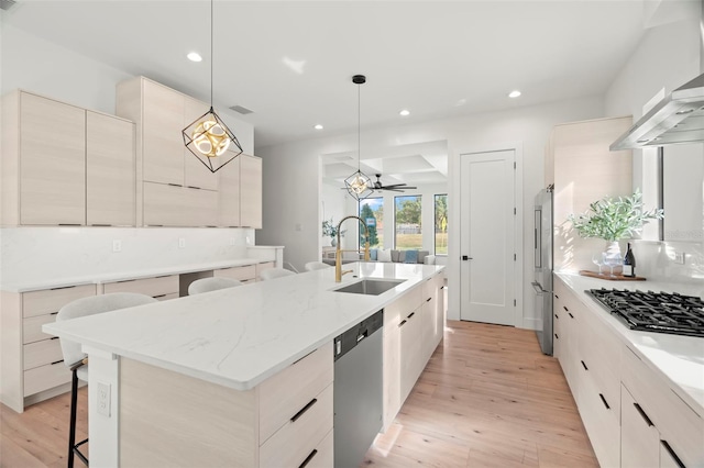 kitchen with a breakfast bar, a center island with sink, sink, decorative light fixtures, and stainless steel appliances