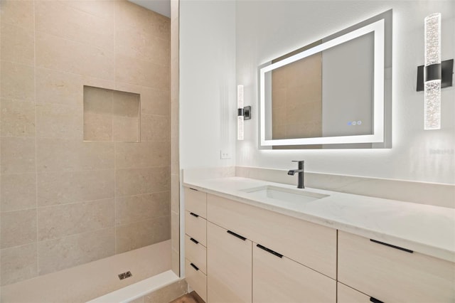 bathroom with tiled shower and vanity