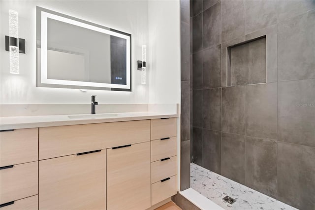 bathroom with tiled shower and vanity