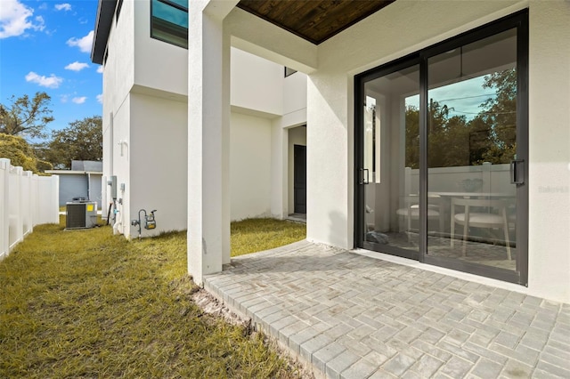 doorway to property with a yard, a patio, and cooling unit