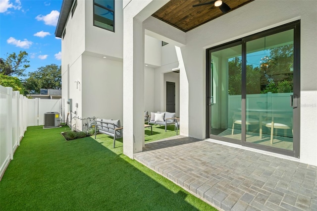 view of exterior entry featuring a lawn, outdoor lounge area, ceiling fan, central air condition unit, and a patio