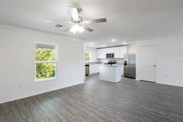 kitchen with hardwood / wood-style floors, a center island, ceiling fan, appliances with stainless steel finishes, and white cabinetry