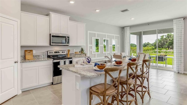 kitchen featuring stainless steel appliances, sink, a center island with sink, and white cabinets