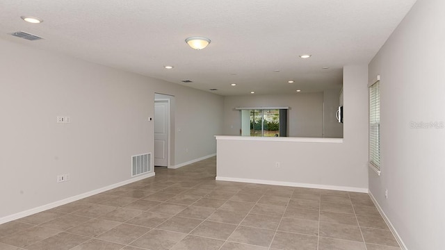 empty room with a textured ceiling and light tile patterned flooring