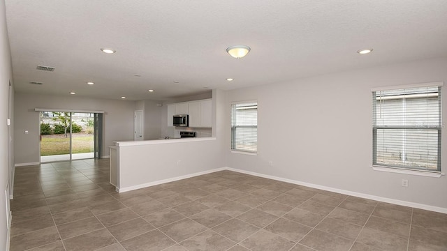 empty room with a textured ceiling and light tile patterned floors