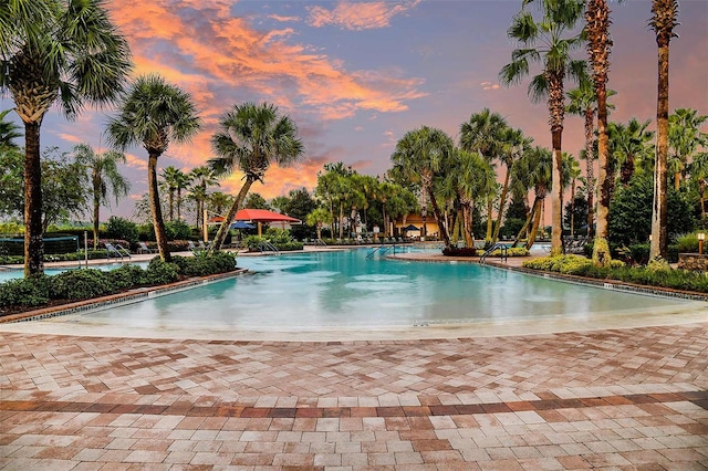 pool at dusk featuring a patio area