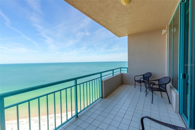 balcony with a water view and a view of the beach