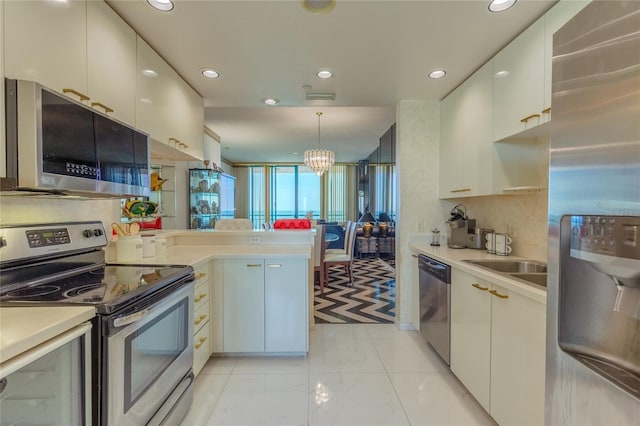 kitchen with pendant lighting, backsplash, an inviting chandelier, kitchen peninsula, and stainless steel appliances