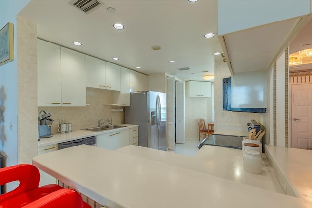 kitchen featuring white cabinets, sink, a kitchen bar, kitchen peninsula, and stainless steel appliances