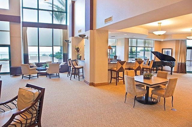 dining area with light carpet and a high ceiling