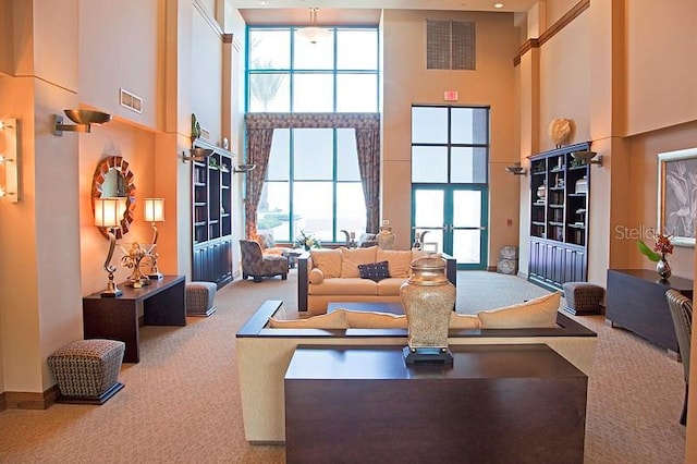 carpeted living room featuring french doors and a towering ceiling