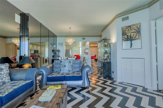 living room with a notable chandelier, ornamental molding, and a textured ceiling