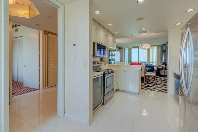 kitchen with an inviting chandelier, white cabinets, appliances with stainless steel finishes, decorative light fixtures, and kitchen peninsula